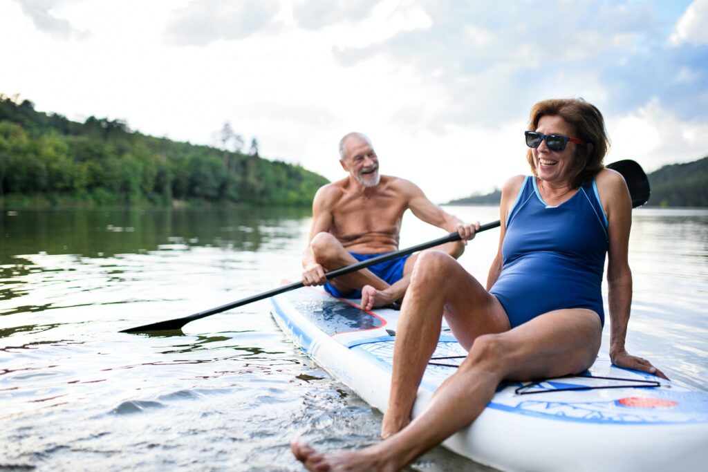 Senior couple paddleboarding on lake in summer